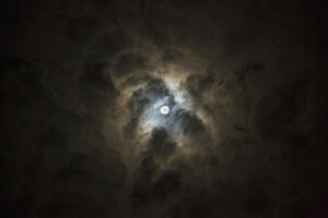 Maan schijnt door donkere wolken