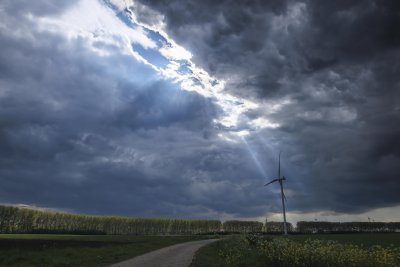 Moody storm clouds hover over a wind turbine in a rural landscap
