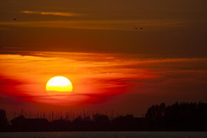 Levendige rode zonsondergang boven brede rivier