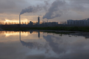Industrieel complex bij schemering, weerspiegeld in plas