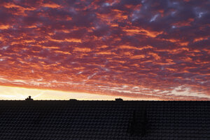 Vurige zonsondergang boven huissilhouetten