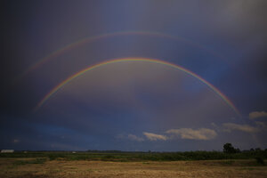 Kleurrijke regenboogbogen boven groen veld