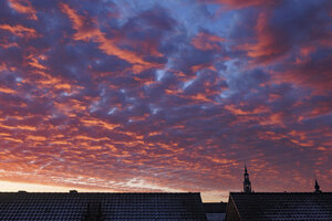 Vibrant sunset casts colorful hues over rooftops in a tranquil e