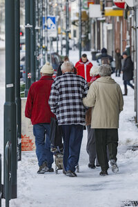 Oudere stellen wandelen samen door besneeuwde straat