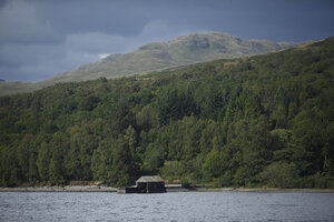 Hutje aan bergmeer omgeven door bos