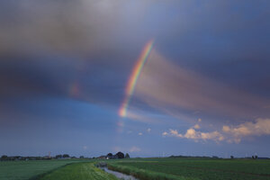 Regenboog glans over groene velden in late namiddag