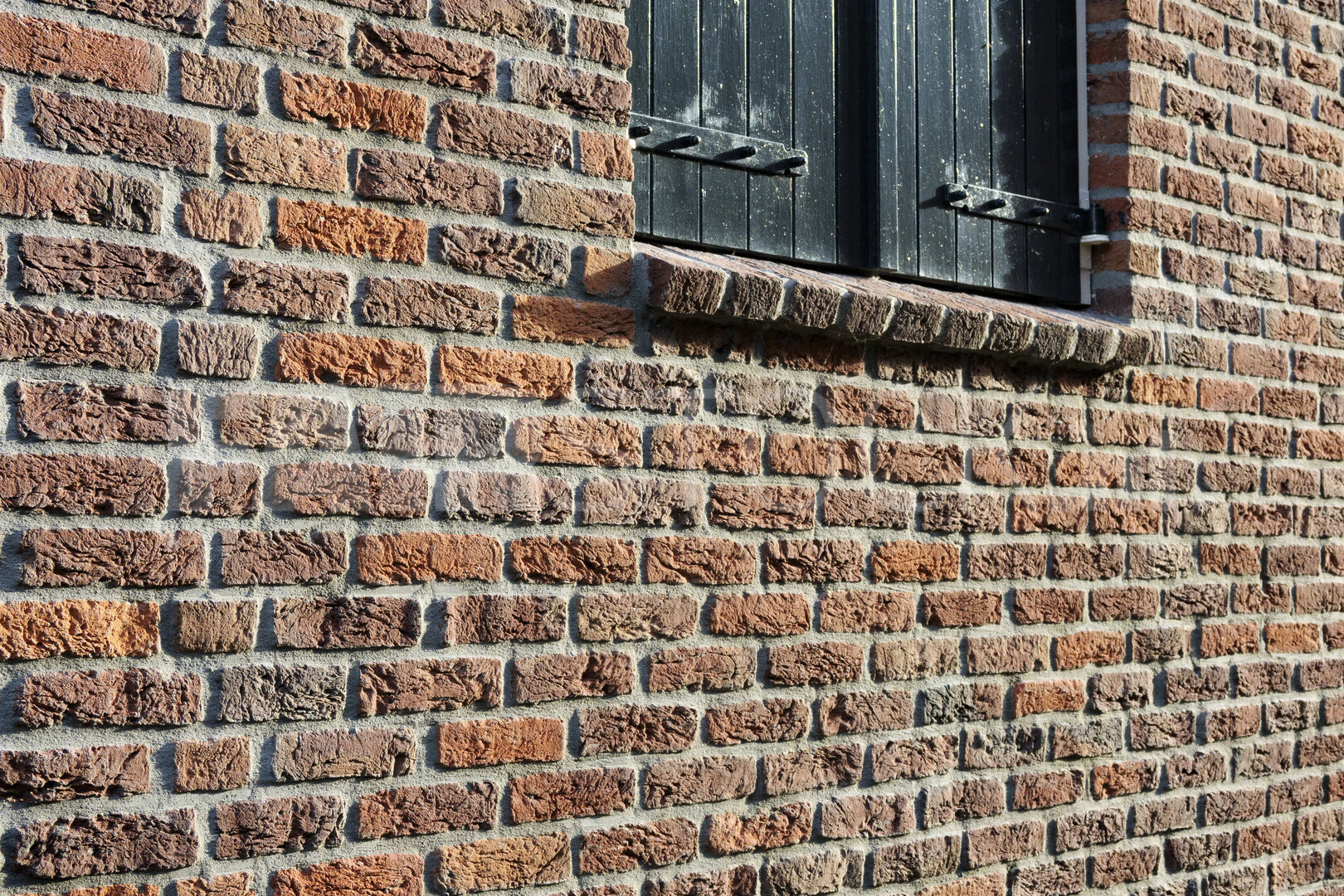 Historic brick wall and black wooden shutters in Noord-Brabant, 