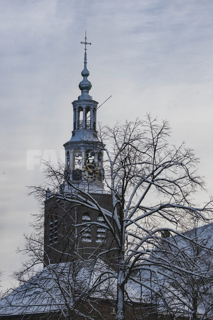 Sneeuwbedekte kerktoren tegen grijze winterlucht