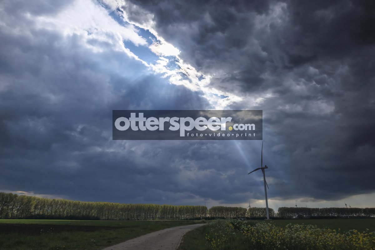 Moody storm clouds hover over a wind turbine in a rural landscap