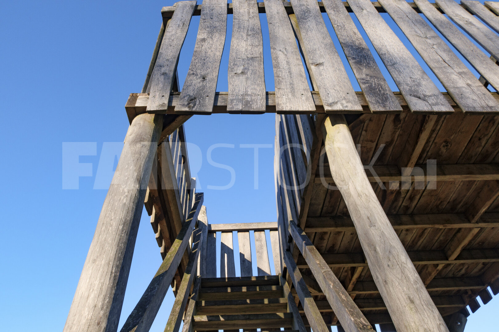 Wooden observation tower under a clear blue sky in a tranquil ou