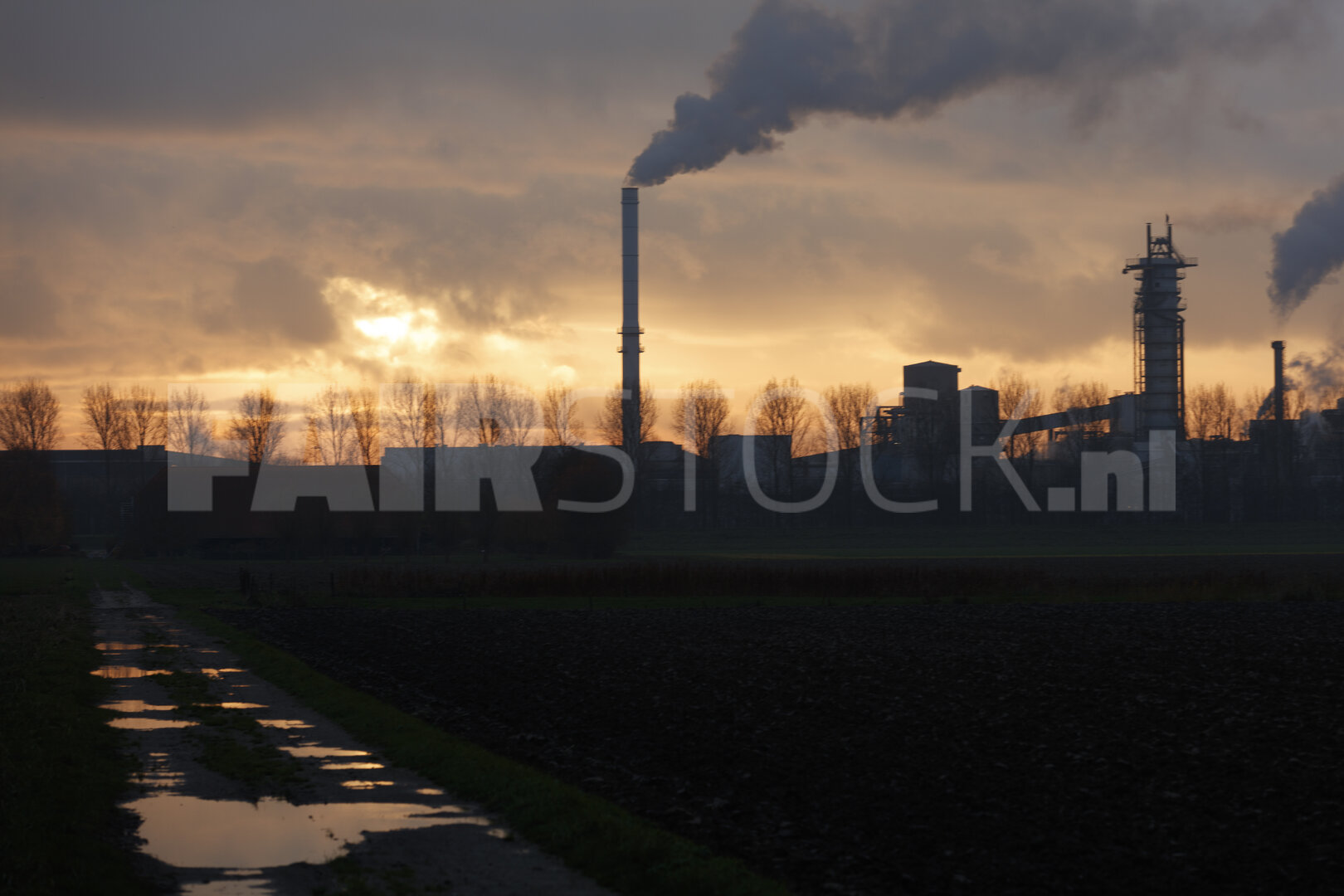 Industriecomplex bij zonsondergang, rookpluimen