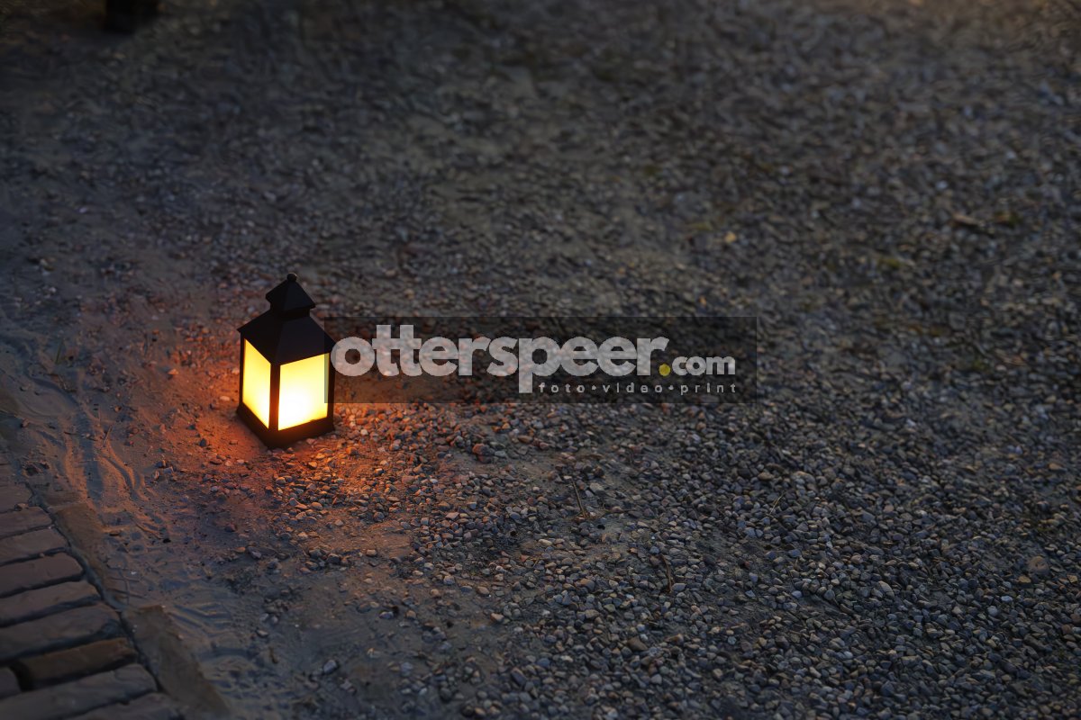 Lantern glowing softly on a gravel path during an evening gather