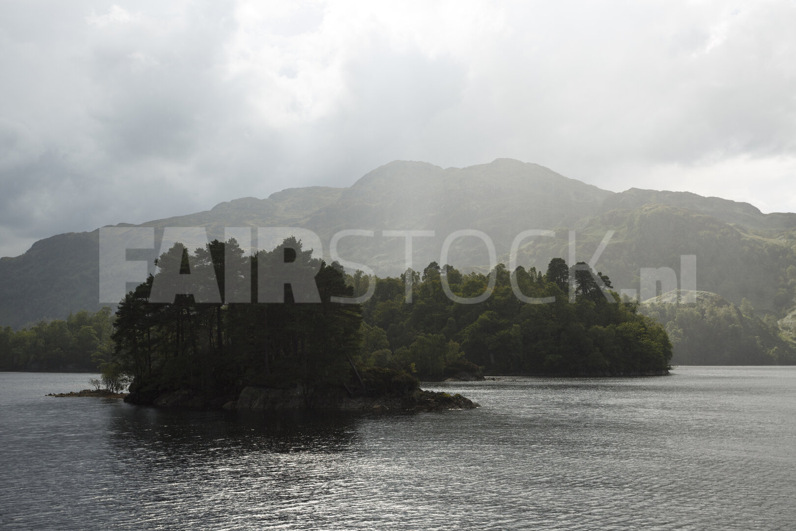 Mistig meer met eiland en bergachtergrond