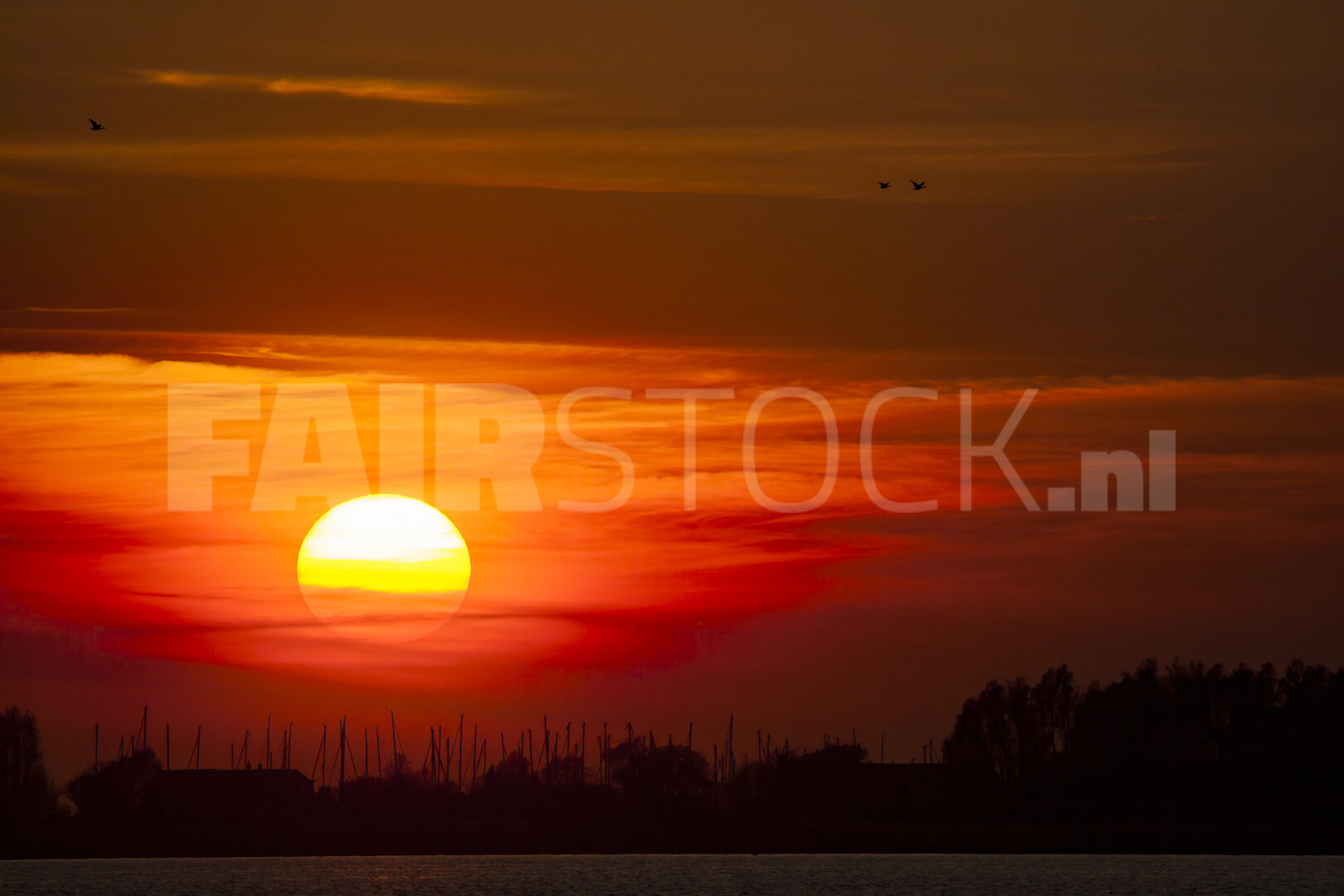 Levendige rode zonsondergang boven brede rivier