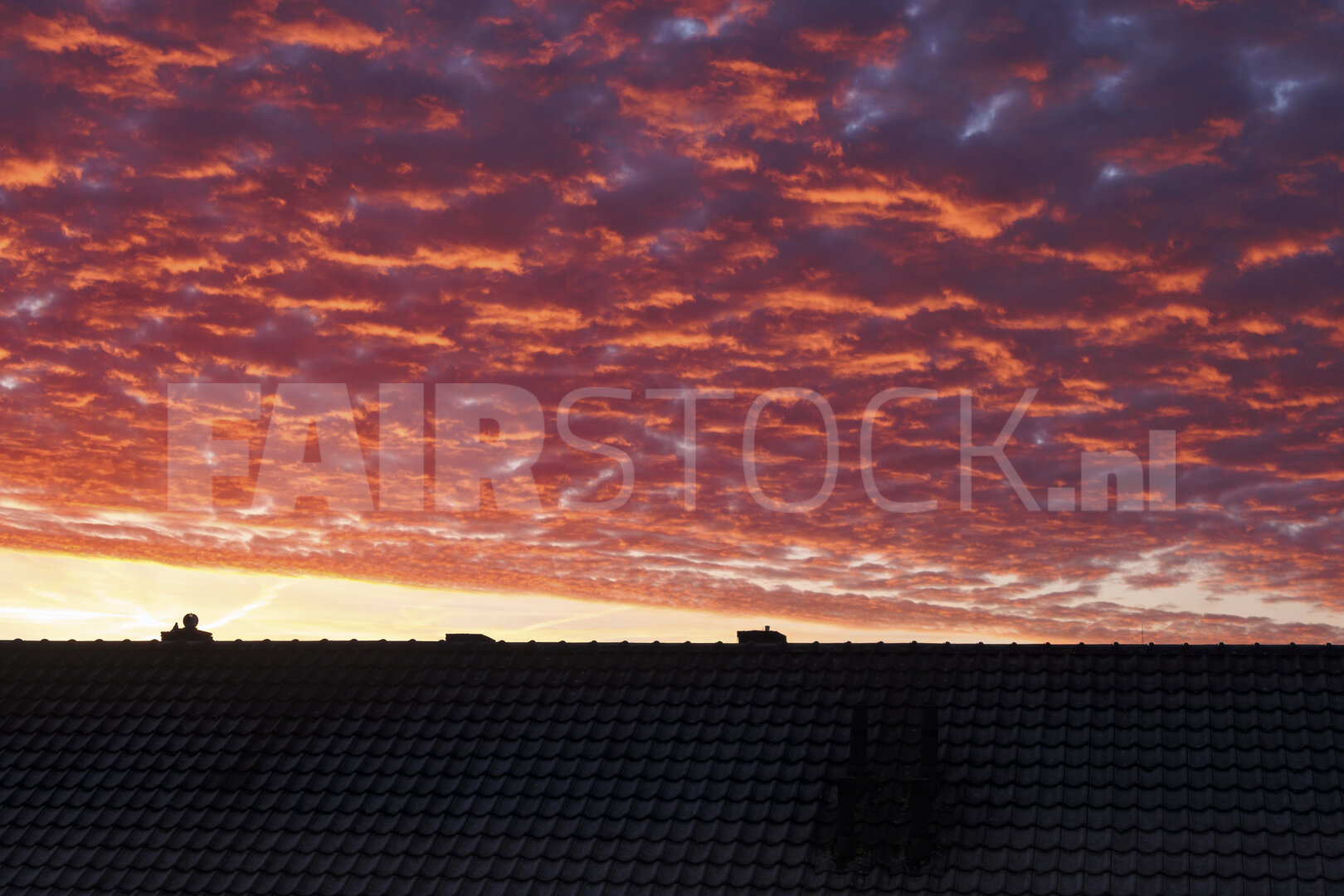 Vurige zonsondergang boven huissilhouetten
