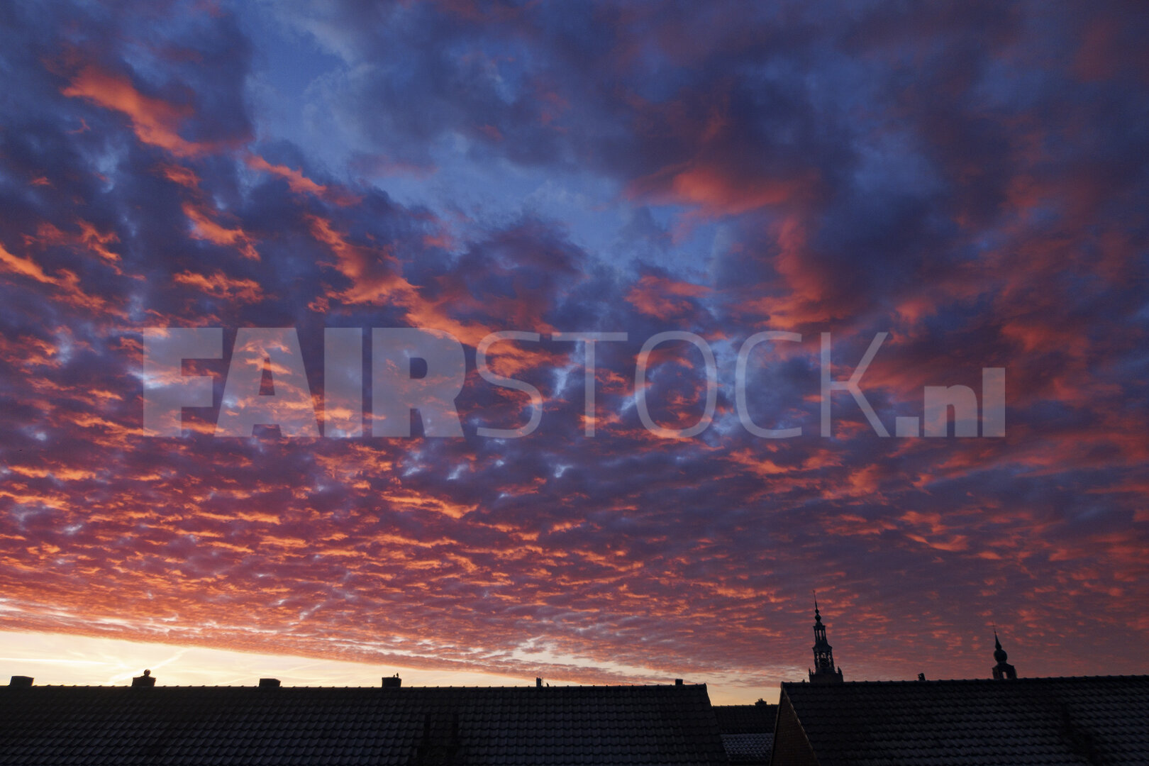 Spectaculaire zonsondergang boven dakeinden