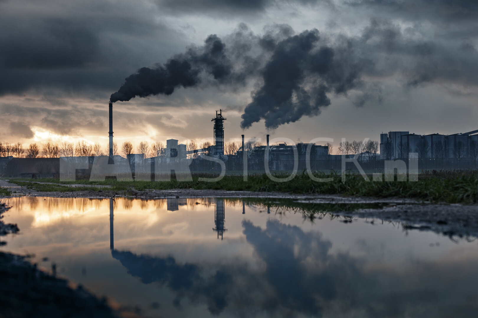 Industriecomplex bij schemering, rook en reflectie