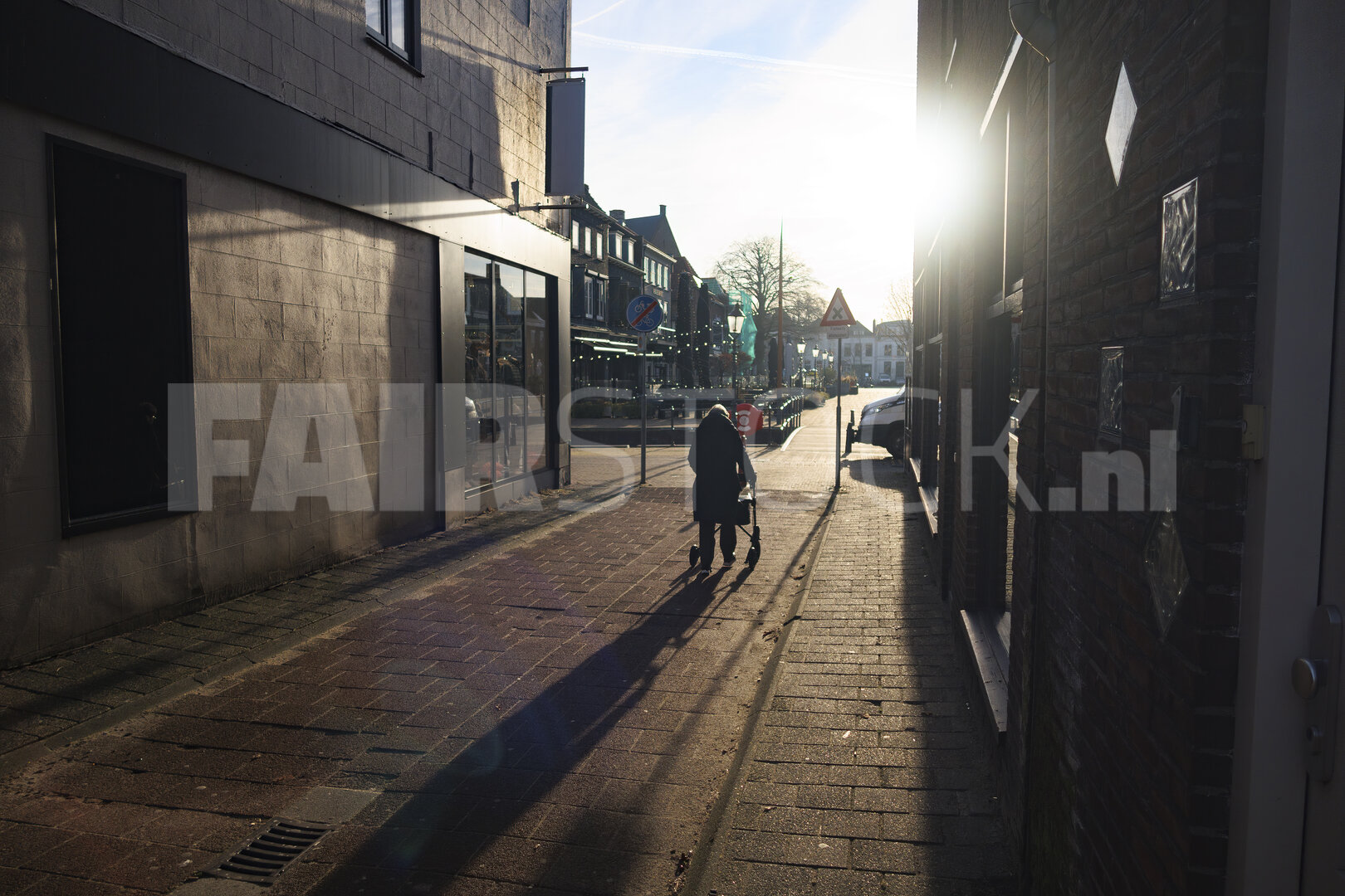 Elderly woman with walker navigating a quiet street in a histori