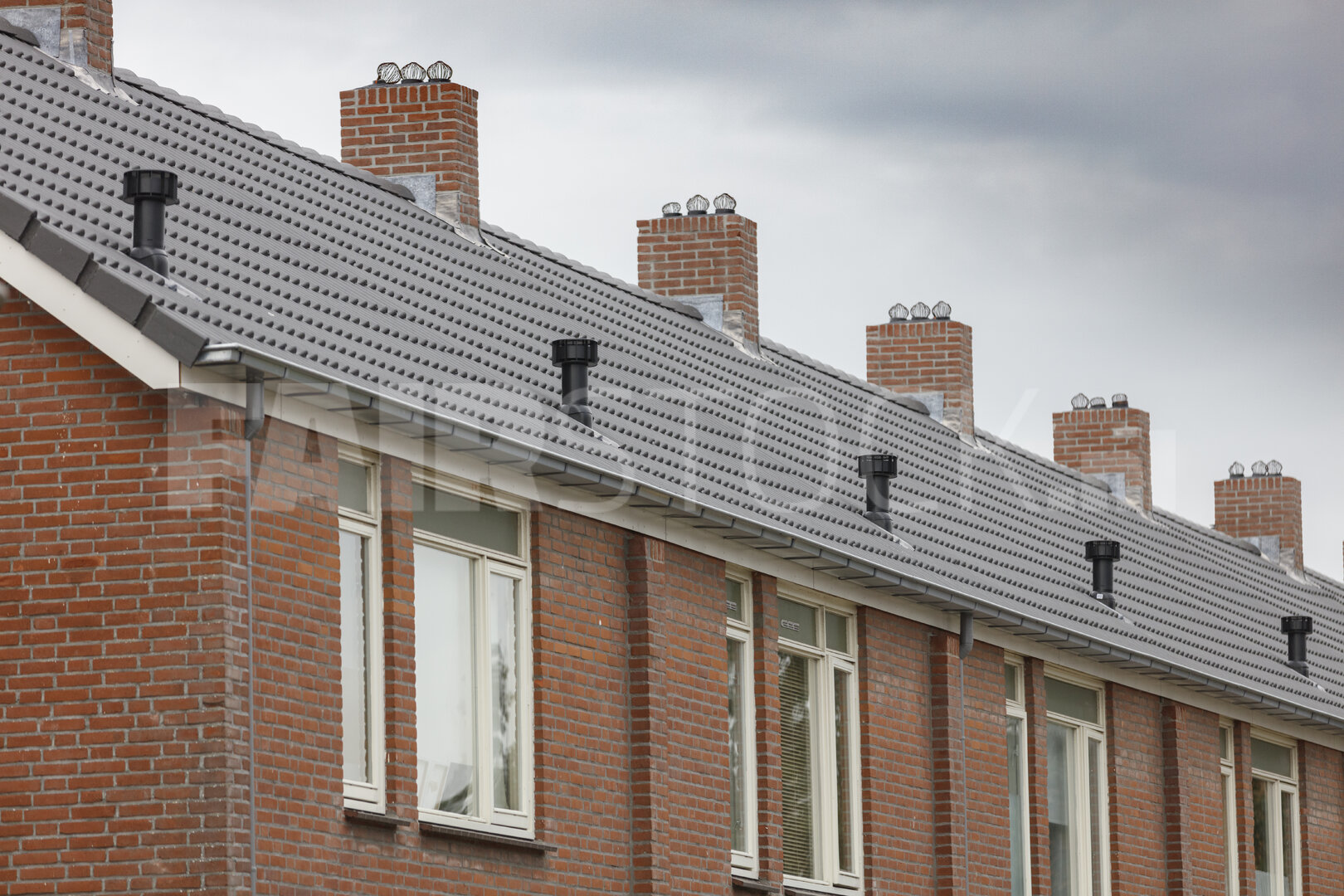 Rij bakstenen huizen met grijze daken