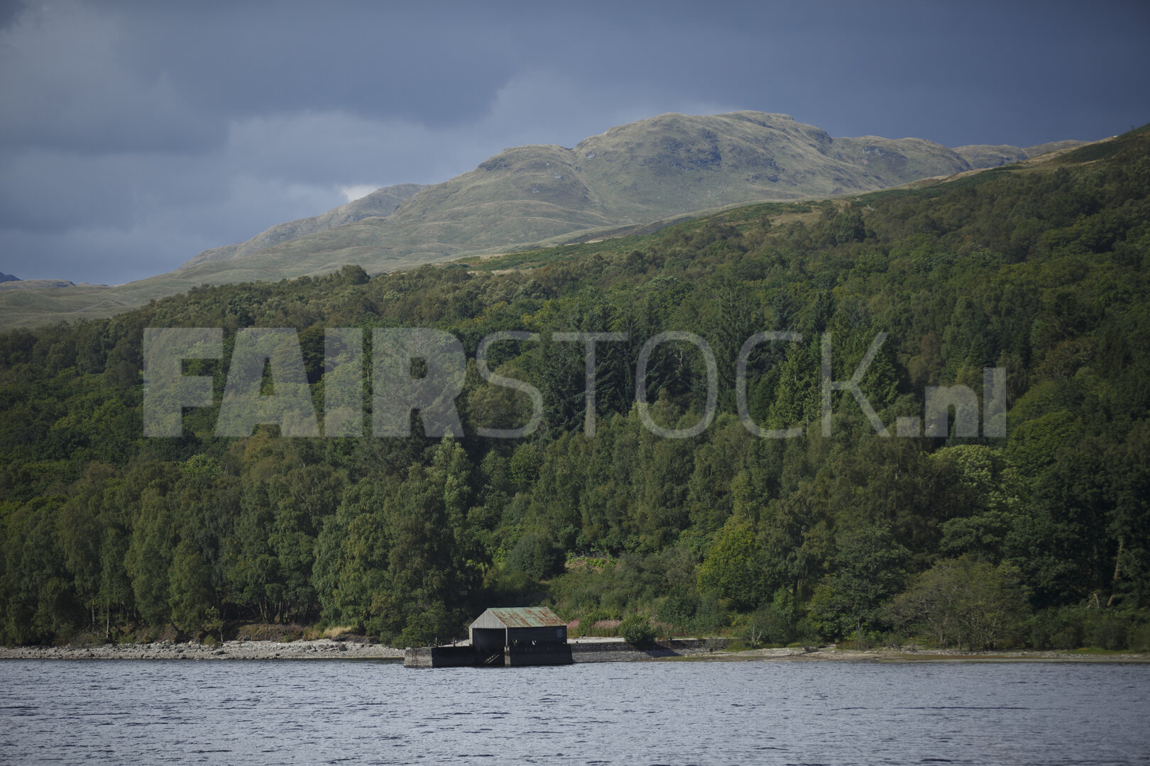 Hutje aan bergmeer omgeven door bos