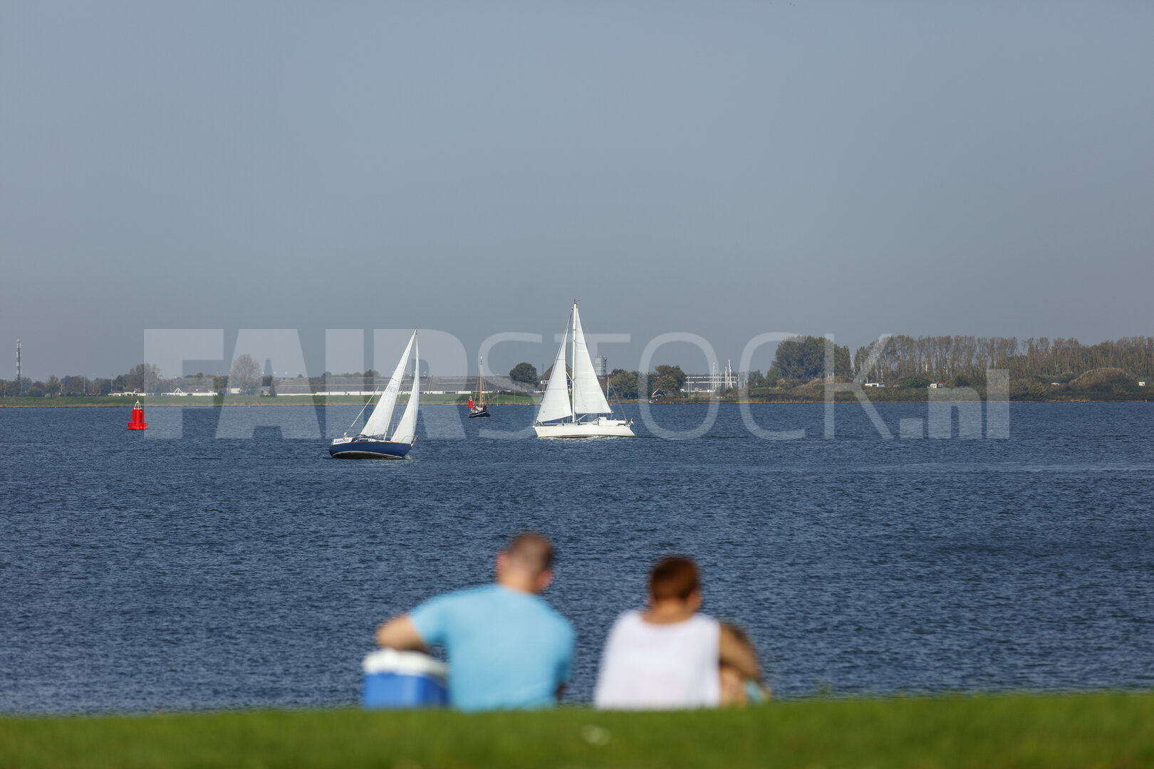 Stel kijkt naar zeilboten op kalm meer