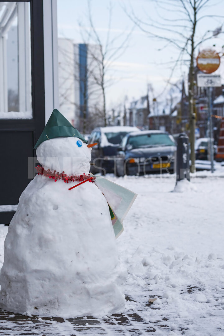 Sneeuwpop met blauwe feesthoed in de sneeuw